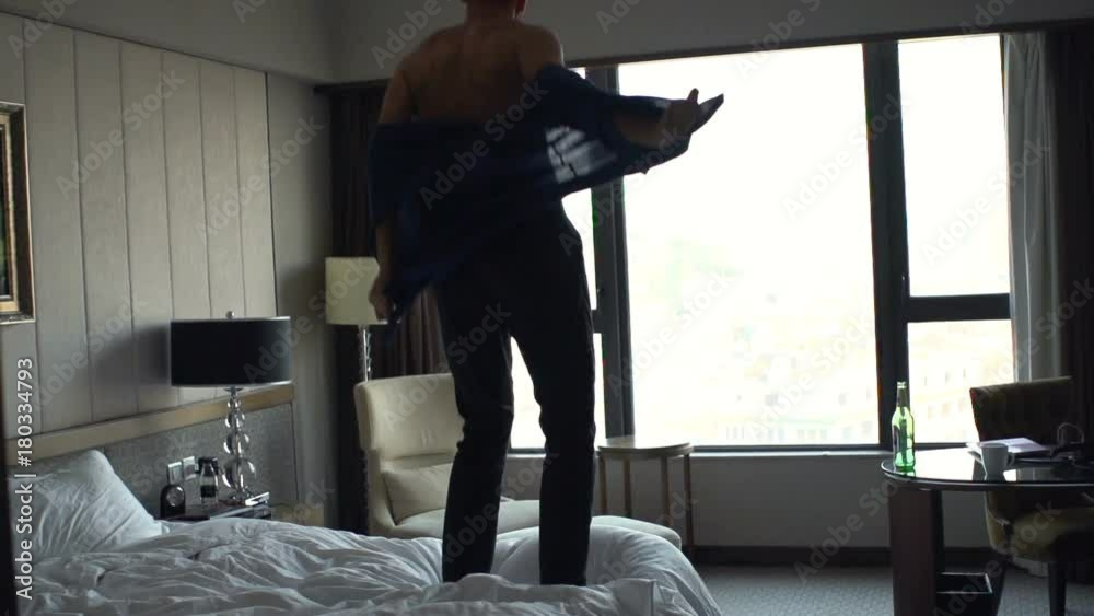 Happy man jumping on bed at home, super slow motion 240fps
