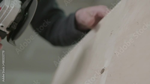 Male carpenter working with electric tools on wooden plank in workshop. Slow motion shot of wood polishing machine in use. TYoung carpenter polishes board. photo