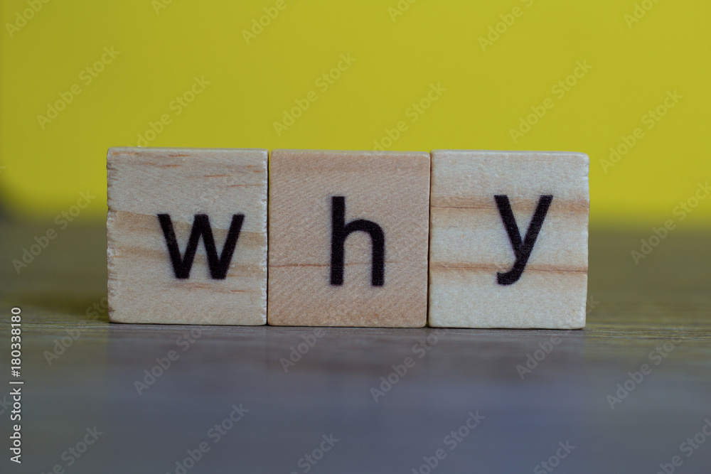 Question word why on wood cubes on table against yellow background Question word why on wood cubes on table against yellow background