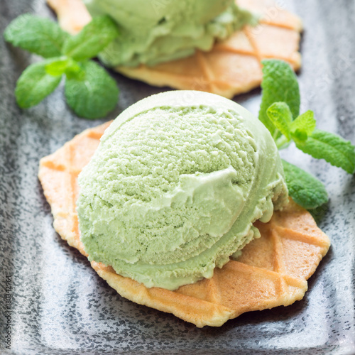 Matcha green tea ice cream balls served with waffles on a black plate, square format