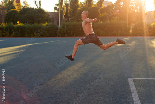 A man athlete starts to run, jumps in the stadium