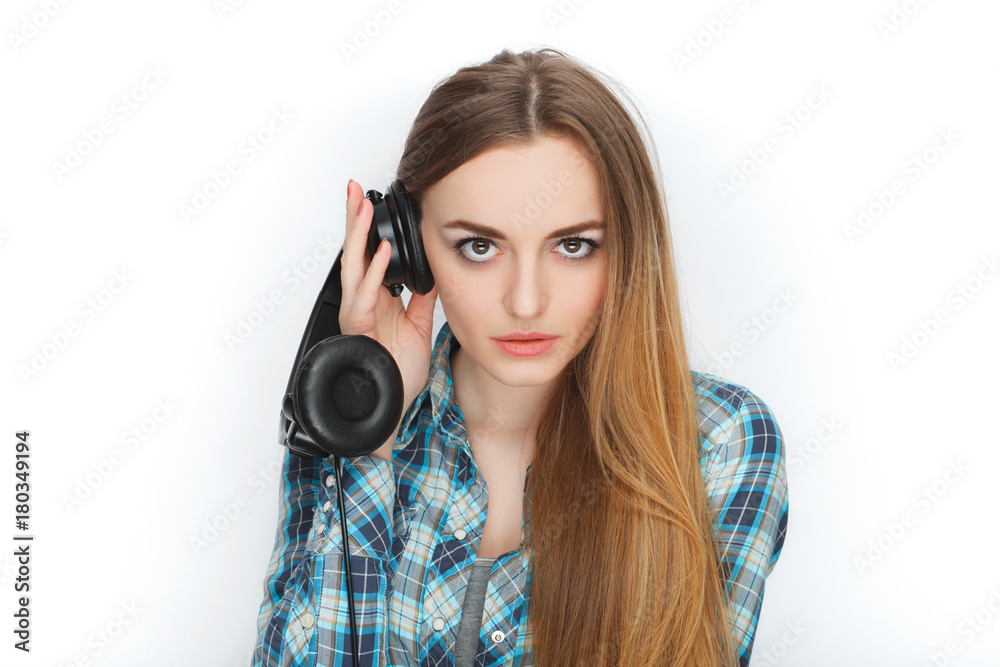 Headshot of a young adorable blonde woman in blue plaid shirt enjoying listening music to big professional dj headphones. Headshot of a young adorable blonde woman in blue plaid shirt enjoying listening music to big professional dj headphones.