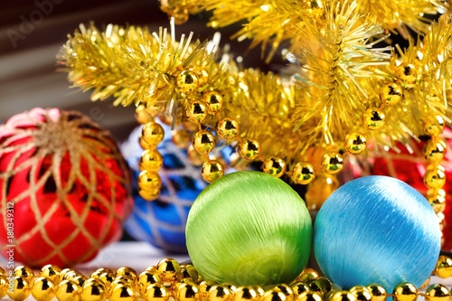 Golden christmas tree with decorated balls and light beams on dark background.