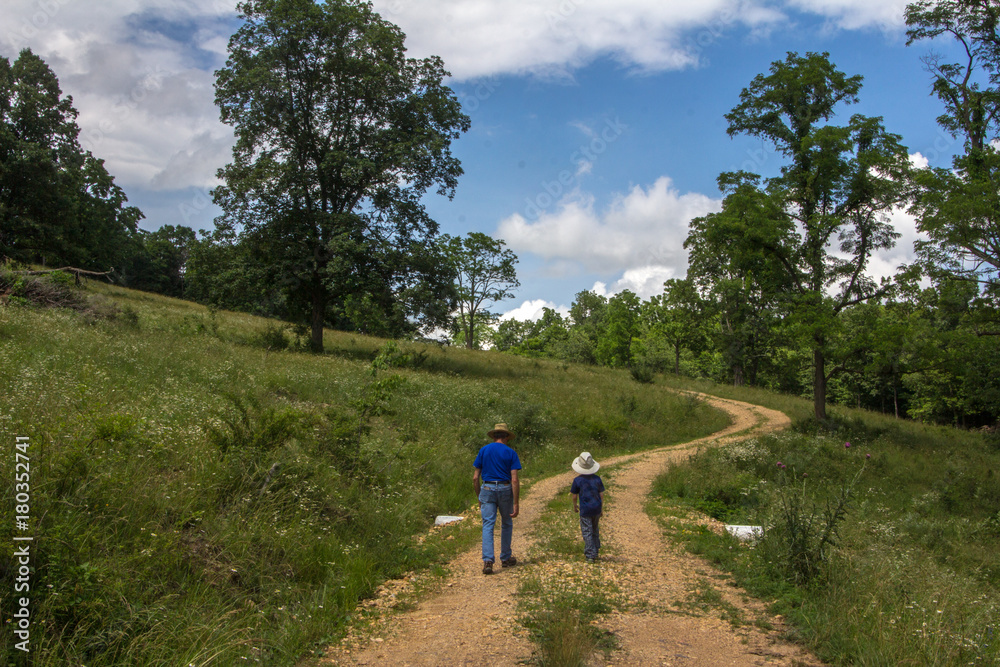 Man and boy walking up a dirt road.