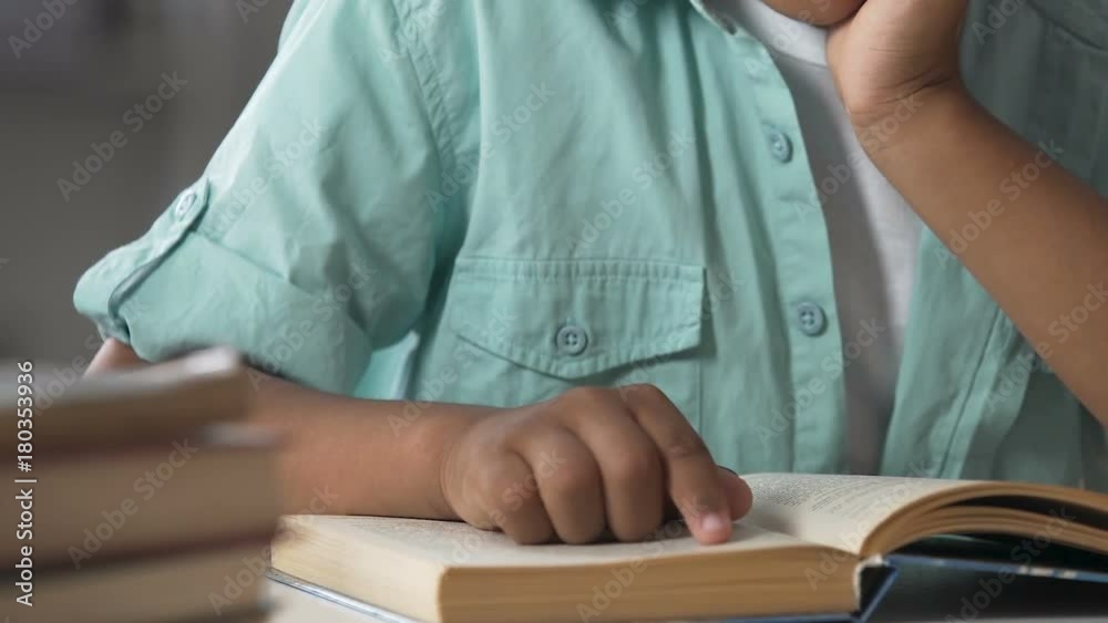 Small child having difficulties with reading book, following lines with finger Small child having difficulties with reading book, following lines with finger