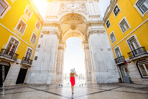 Young woman tourist in red dress standing back in front of the famous triumphal arch in Lisbon city center in Portugal photo