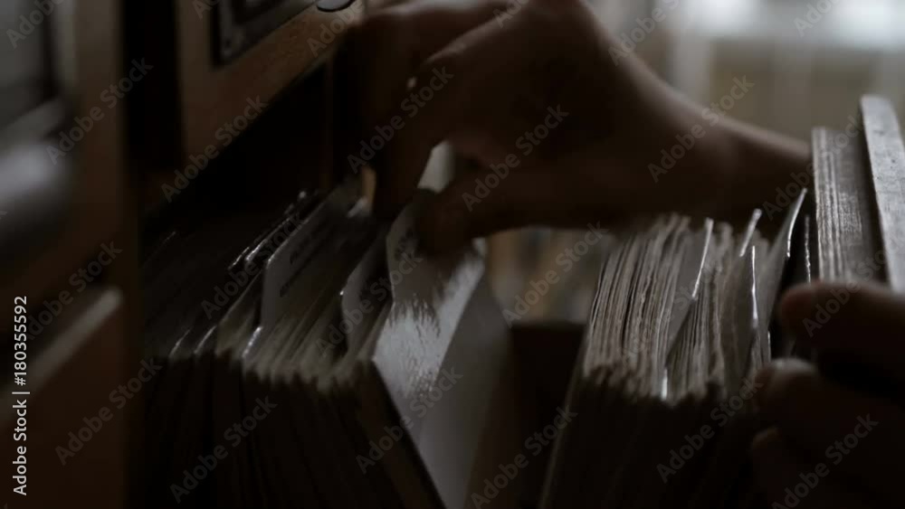 Girl student looking for a book in the library card catalog