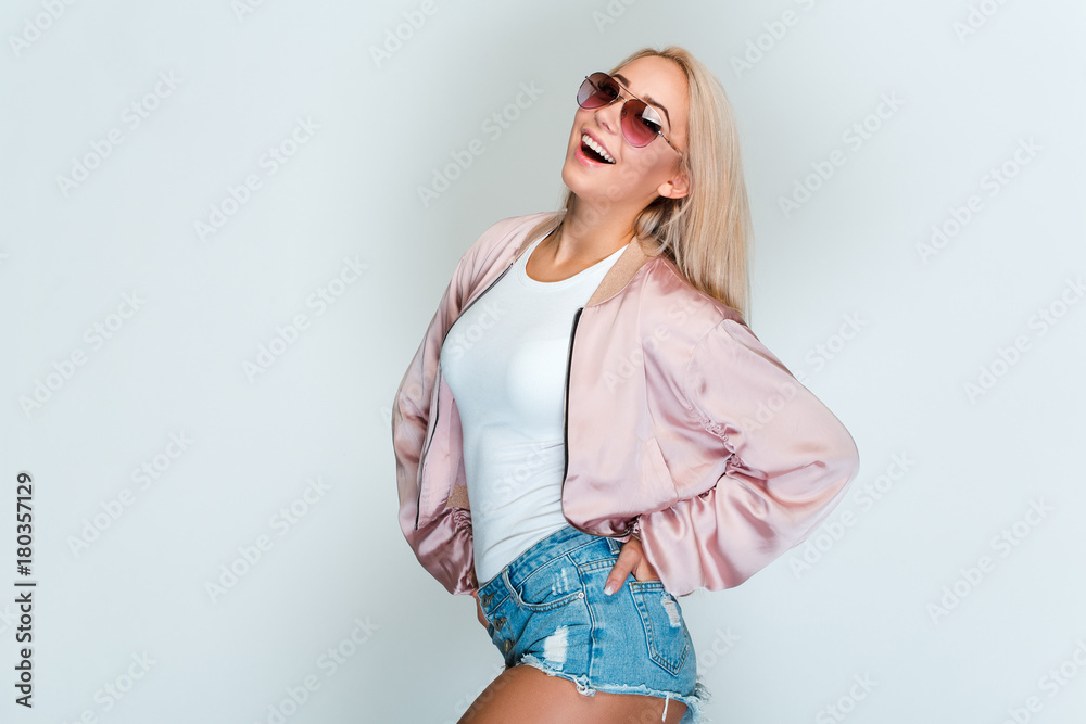 Astonishing beauty! Beautiful young woman with blond hair looking at camera with smile while standing against grey background Astonishing beauty! Beautiful young woman with blond hair looking at camera with smile while standing against grey background