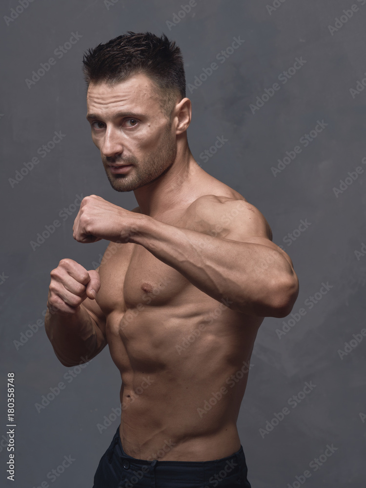 A physically strong man in black trousers and a naked torso. A physically strong man in black trousers and a naked torso.