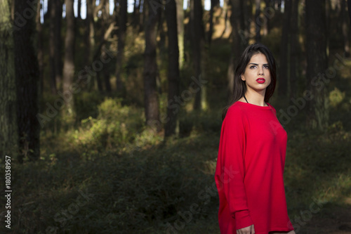 Beautiful young woman in the woods dressed in red