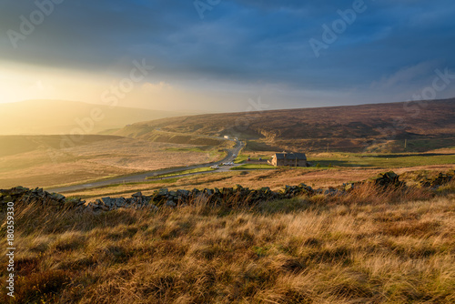 Beautiful autumn scenery in the Peak District - sun setting over Macclesfield road and Peak View Tea Rooms, scenic valley in the distance with dramatic storm clouds 