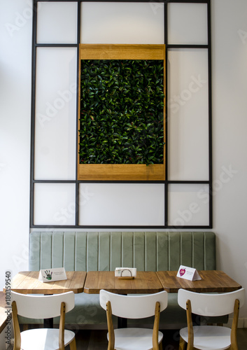 Conceptual shot in restaurand fast-food table aith white chairs and green sofa and cavas with leaves