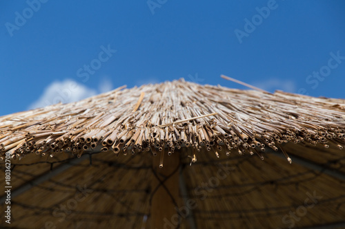 Straws on the roof of the beach hut umbrella with blue sky background
