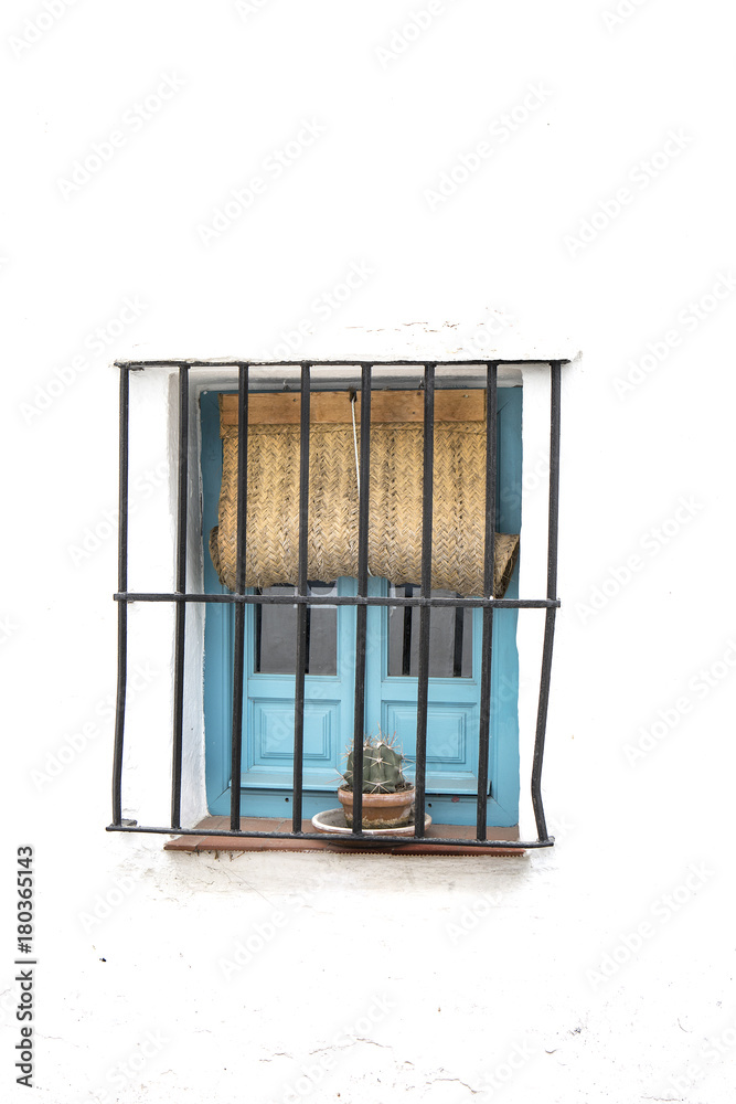ventana pintada de azul con barrotes de hierro forjado y persiana de  esparto en pared blanca encalada foto de Stock | Adobe Stock