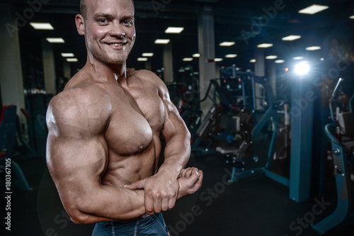 Handsome model young man training arms in gym