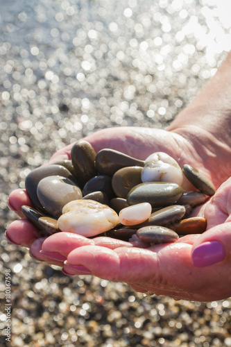 Sea stones in hands on the beach in the summer