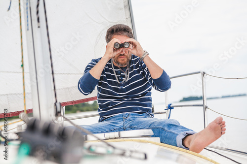 man sits on sailing yacht and looks through binoculars