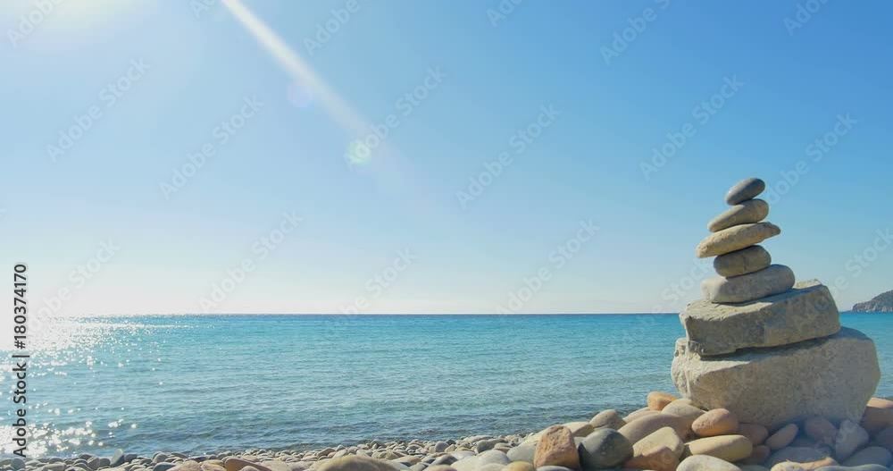 Waves landing on stone beach. Meditation, stone pyramide. Clear blue water. Waves landing on stone beach. Meditation, stone pyramide. Clear blue water.