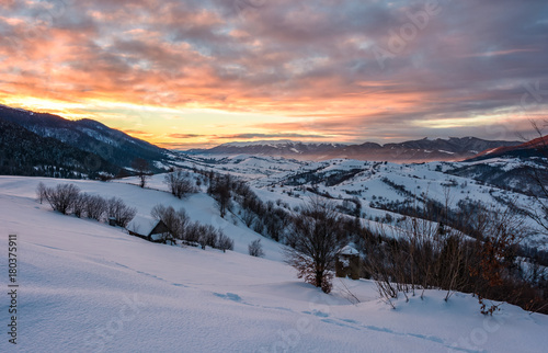 winter dawn in mountainous countryside. gorgeous cloudy sky over the snow covered hills. wide mountain ridge in a far distance © Pellinni
