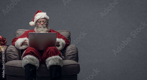 Santa Claus connecting with a laptop photo