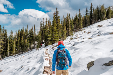 Tourist with backpack hiking on snowy trail