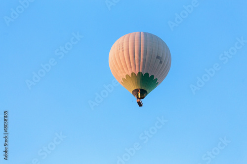 One hot air balloon flying at blue sky background at sunrise in the morning