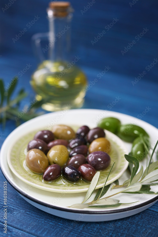Plate with olives and oil on color wooden background Plate with olives and oil on color wooden background