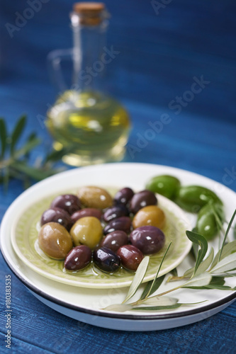 Plate with olives and oil on color wooden background