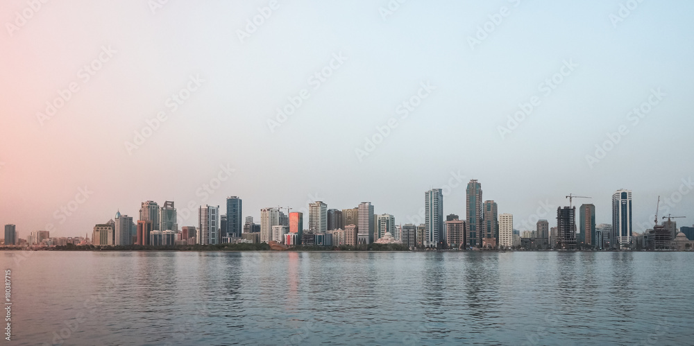 Fototapeta premium The Emirate Of Sharjah. Evening landscape of the city promenade with walking people and architecture.
