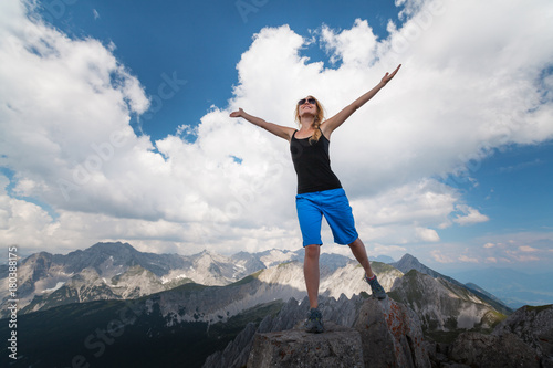 Young lady standing on top of the hill with raised hands