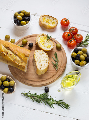 Black and green olives in wooden bowls on wood white background.