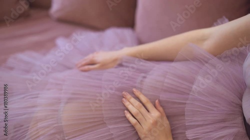 The hands of the model lie on a tulle skirt of lavender color and stroke it. long evening dress. 4k