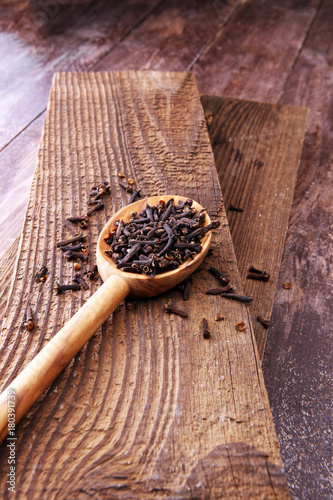 Many Dry cloves spice on brown wooden spoon.