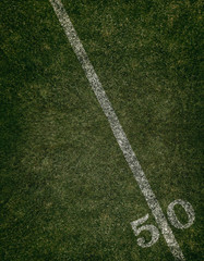 Football field ground fifty yard line. Friday night lights.
