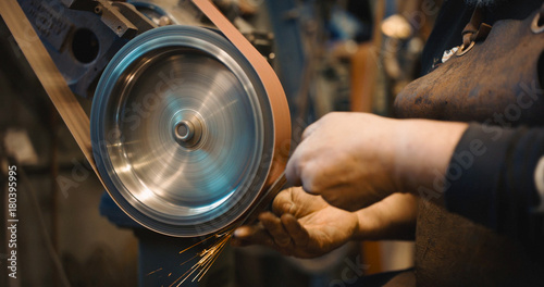 Craftsman uses a belt sander in machine shop. photo