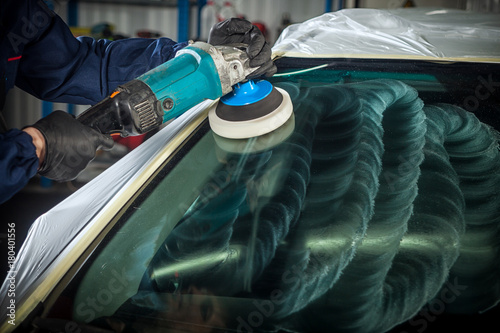 Canvas-taulu Close-up of a male mechanic with a blue prism and protective gloves polishes the