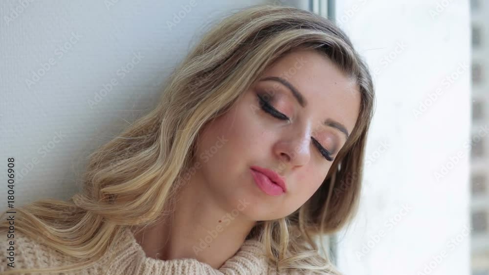 Beautiful young woman in sweater sitting on the window and resting, close-up. Beautiful young woman in sweater sitting on the window and resting, close-up.