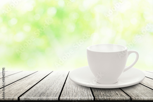 hot espresso with white ceramic coffee cup on wood table nature background blurred in garden.