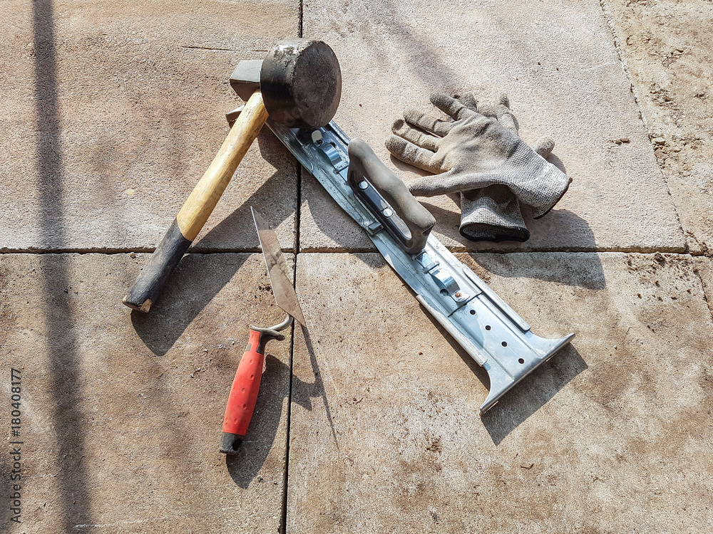 Verschiedene Werkzeuge Hammer Kelle und Plattenheber für Pflasterarbeiten  mit Gehweg Platten Photos | Adobe Stock