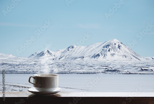 Cup of hot drink with steam on wooden desk and beautiful winter landscape view in the morning © SasinParaksa