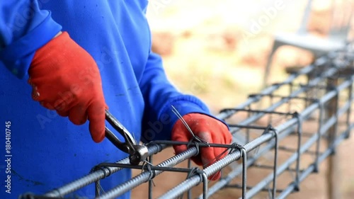 Workers hand holding wire and binding with steel by pliers at construction site