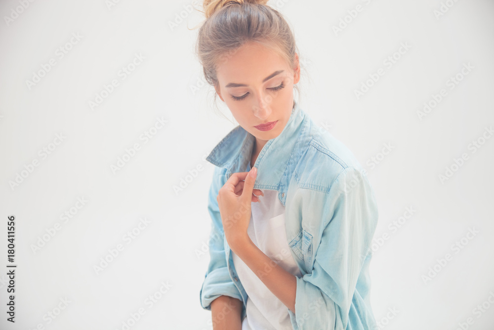 blonde casual woman holding shirt's collar and looks down blonde casual woman holding shirt's collar and looks down