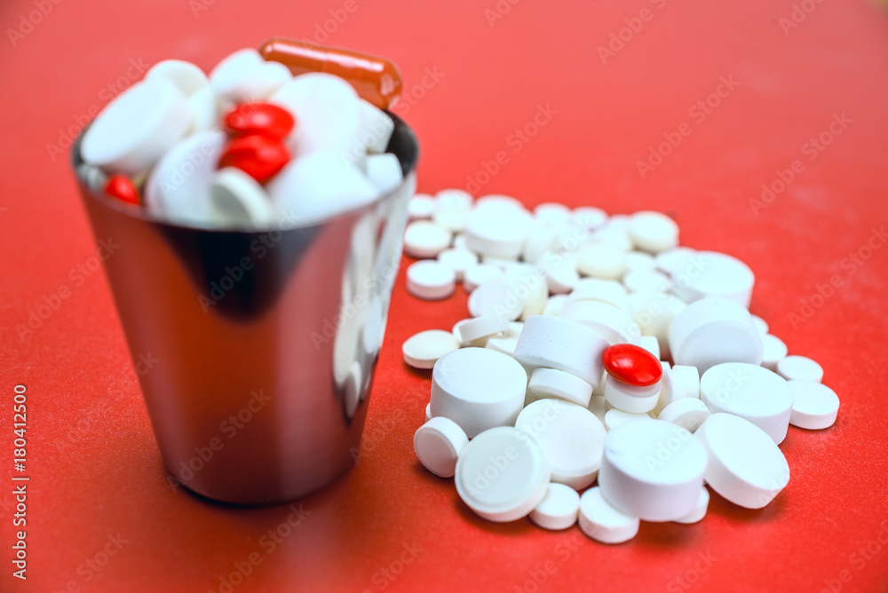 tablets in a metal bucket on a red background tablets in a metal bucket on a red background