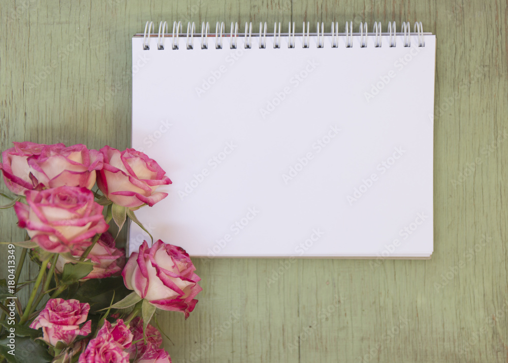 Blank notebook mock up for artwork with pink roses. Place for text. Fresh flowers on old wooden background. Blank notebook mock up for artwork with pink roses. Place for text. Fresh flowers on old wooden background.