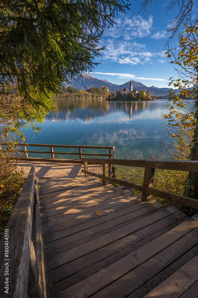 Bled, Slovenia - Wooden stairs and pier at the beautiful Lake Bled with the famous Pilgrimage Church of the Assumption of Maria with Bled Castle and Julian Alps at background