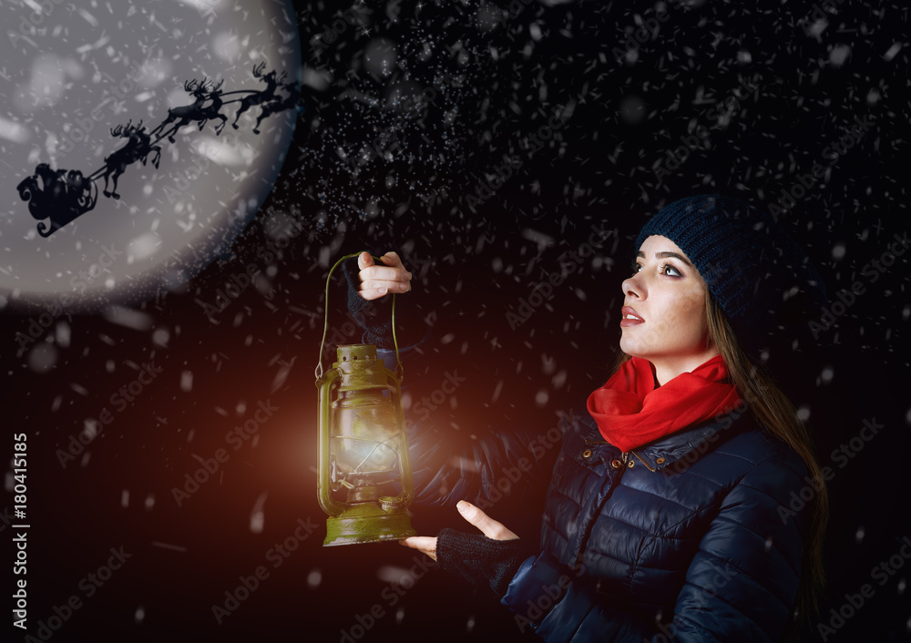 Fototapeta premium Girl with lantern at Christmas night pointing the way for Santa Claus