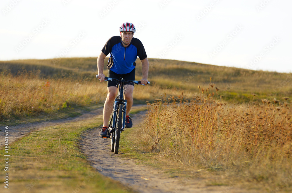Fototapeta premium Male cyclist driving by rural dirt road outdoors