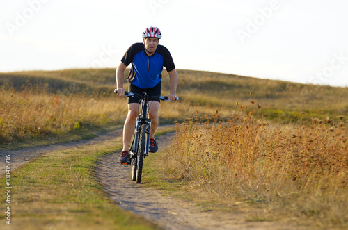 Male cyclist driving by rural dirt road outdoors © Mikhailov Studio
