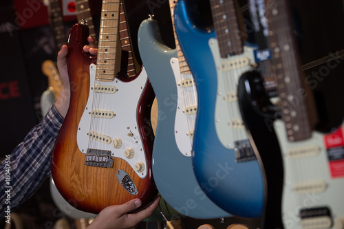 Many electric guitars hanging on wall in the shop