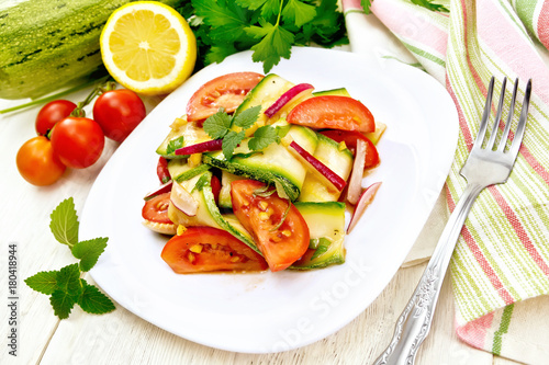 Salad with zucchini and tomato in plate on light board
